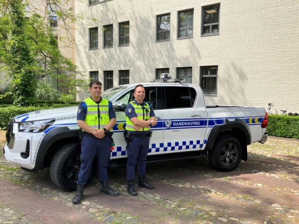 Volledig zijaanzicht van Toyota Hilux handhavingsvoertuig Gemeente Meerssen met handhavers in beeld